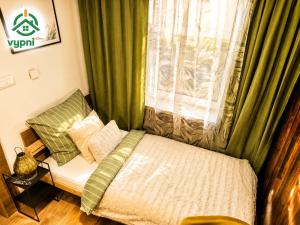 a bed in a room with a window with green curtains at Chalupa Oslany in Oslany +34 photos