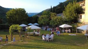a group of people sitting in chairs under white umbrellas at Albergo dell'Angelo in Pieve di Teco
