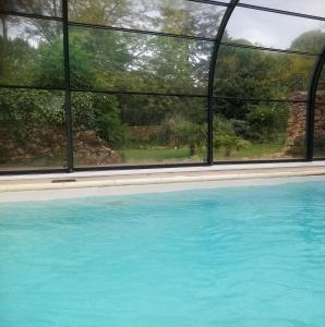 a swimming pool with blue water and a window at Le Figuier , Domaine La Capitainerie in Bazoges-en-Pareds