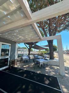 a patio with tables and chairs and a tree at Marina Estensi Floating Resort - Classic Yacht in Lido degli Estensi