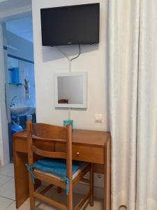 a desk with a chair and a television on a wall at Angelos Studios in Ilia
