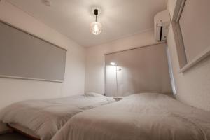 a white bedroom with two beds and a light at 一軒家貸切 THREE FIELD Kobe Nakayamate in Kobe