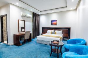 a hotel room with a bed and a desk and chairs at Taleen Serviced Apartments Granada- تالين غرناطة للشقق المخدومة in Riyadh +29 photos