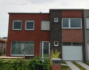 a red brick house with two white garage doors at B-SIDE Loppem in Zedelgem