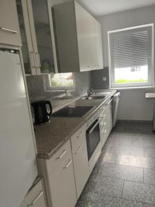 a kitchen with white cabinets and a sink and a refrigerator at Ferienwohnung Habichtswald in Habichtswald