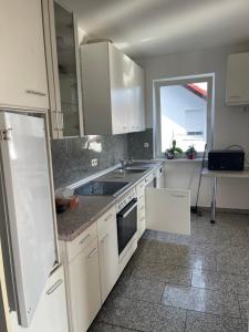 a kitchen with white cabinets and a sink at Ferienwohnung Habichtswald in Habichtswald