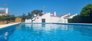 a swimming pool in front of a white house at Villa Audrey in Cala en Bosc