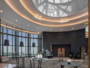 a lobby with a large circular ceiling with tables and chairs at Fairmont Riyadh in Riyadh +289 photos