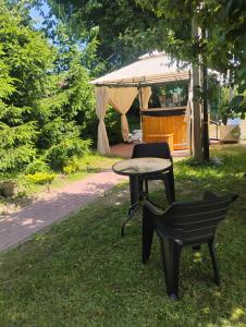 a table and a bench in a park with a tent at Lipowy domek Mazury in Piecki