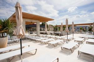 a patio with white lounge chairs and umbrellas at Magnum in Berehove