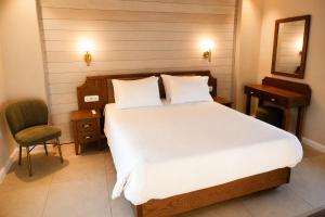 a bedroom with a large white bed and a chair at Athena Collection in Kefalos