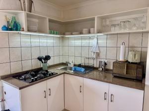 a kitchen with white cabinets and a stove top oven at Pebbles & Shells in Kleinmond