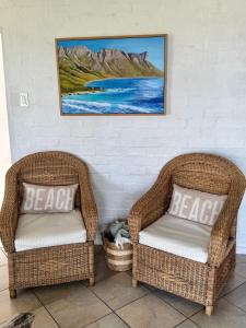 two wicker chairs sitting next to a wall at Pebbles & Shells in Kleinmond