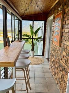 a room with a table and chairs and a brick wall at Pebbles & Shells in Kleinmond