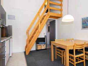a kitchen and dining room with a wooden table and stairs at Premium apartment with loft in holiday park in Ringkøbing