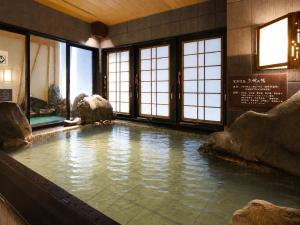 a large pool of water in a room with windows at Dormy Inn Express Mikawaanjo in Anjomachi