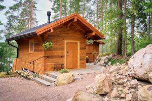 a wooden cabin in the woods with a porch at Forest Cabin Ainola with Lake View next to Nuuksio National Park in Otalampi