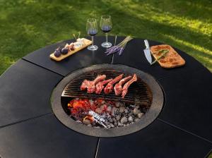 a grill with meat and bread and wine glasses on a table at Qafqaz Front Falcon Chalet in Gabala