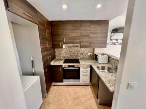 a small kitchen with wooden cabinets and a sink at Perita Apartamentos in Mataró