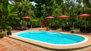 a large swimming pool with red umbrellas in a yard at Nan Seasons Boutique Resort in Nan