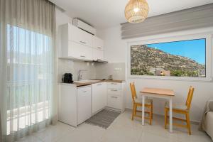 a kitchen with white cabinets and a table and a window at Amalia in Matala