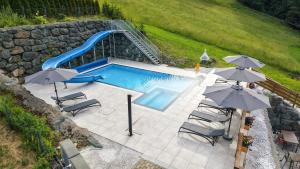 an overhead view of a swimming pool with a slide and umbrellas at Hotel Sonnenalm Stuhleck in Spital am Semmering