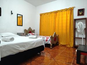 a bedroom with two beds and a yellow curtain at EcoHonda Low Cost in Honda