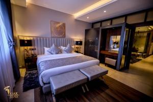 a bedroom with a large bed with a bench in it at Oak Plaza Suites in Kumasi +64 photos