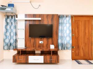 a living room with a tv on a wooden wall at SV Serviced Apartments in Chikmagalūr