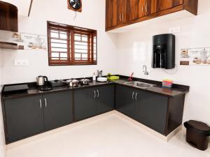 a kitchen with black cabinets and a sink at SV Serviced Apartments in Chikmagalūr