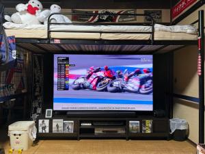 a tv in a living room with a bed and a tvictericterictericter at Rider & Guest House Kazeyoubi in Fukuyama