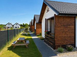 a row of houses with picnic tables and a fence at Domki letniskowe MagNat 700m od morza! in Rusinowo