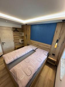a large bed in a room with a blue wall at Villa L'Aida in Canazei