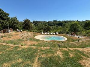 an outdoor swimming pool in a field with chairs at Il Cantuccio delle Crete in Asciano
