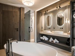 a bathroom with a tub and a sink and a mirror at Hotel Bergkristall Zillertal - Adults Only in Hippach