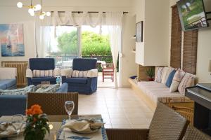 a living room with a couch and chairs and a table at Ammos Lux Apartments in Agia Triada