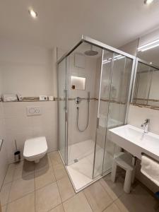 a bathroom with a shower and a toilet and a sink at Hotel Bergheimat in Schönau am Königssee +48 photos