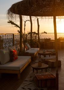 a group of couches and tables with a sunset in the background at The Lodge - Boutique Hotel and Creative Residency in Tamraght Ouzdar