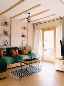 a living room with a green couch and a table at The Lodge - Boutique Hotel and Creative Residency in Tamraght Ouzdar