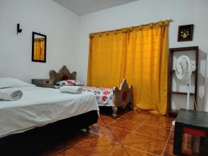 a bedroom with two beds and a yellow curtain at Callejón del Sol in Honda +1 photo