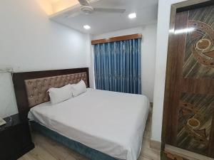 a bedroom with a bed and a blue curtain at Hotel D Palace in Dhaka