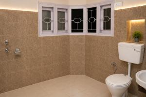 a bathroom with a toilet and a sink and windows at Jannat Hotel - Solan in Solan