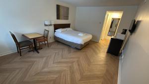 a bedroom with a bed and a table and a television at Midtown Inn Saskatoon in Saskatoon