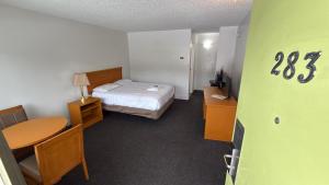 a hotel room with a bed and a desk and a table at Midtown Inn Saskatoon in Saskatoon