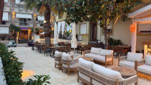 a patio with couches and tables and palm trees at Oniro Rooms & Suites in Leptokarya