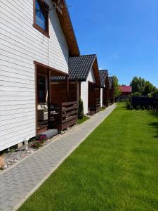 a row of cottages next to a green lawn at Domki letniskowe MagNat 700m od morza! in Rusinowo