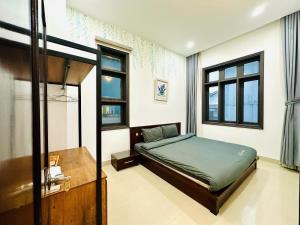 a bedroom with a bed and a desk and windows at Lala VILLA ĐÀ LẠT in Da Thien