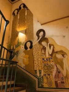 a mural of women on the side of a staircase at La Rocca Sospesa in Apricale