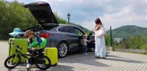 a woman standing next to a car with a child on a bike at Zielone Wzgórza - Centrum Soliny - SPA 695-744-679 in Solina