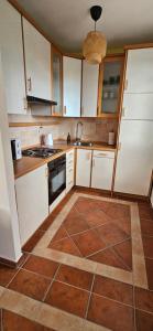 a kitchen with white cabinets and a brown tile floor at Apartment with private pool in Njivice +2 photos